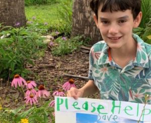 A boy, Brice Claypoole, shows a poster he made about saving Orange Hammock Ranch.